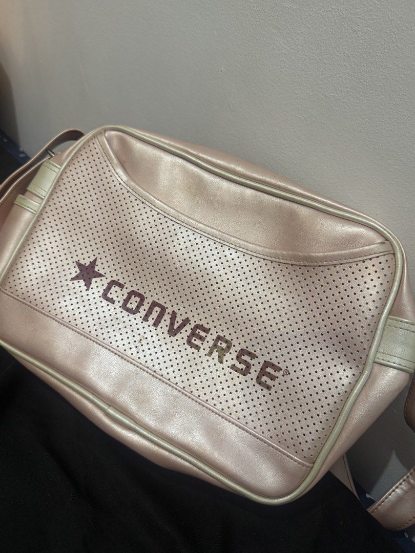 Converse Pink Shoulder Bag (Category: Shoulder Bags) located in Manila. Submitted by sstash444 (Listing ID 1467118242, Image 1). Description: - Brand: Converse - Style: Messenger bag - Color: Pink with red logo lettering - Features: Perforated front panel, zip top opening, and adjustable shoulder strap - Condition: Clean overall shape with minor surface staining near the top trim and front lettering.