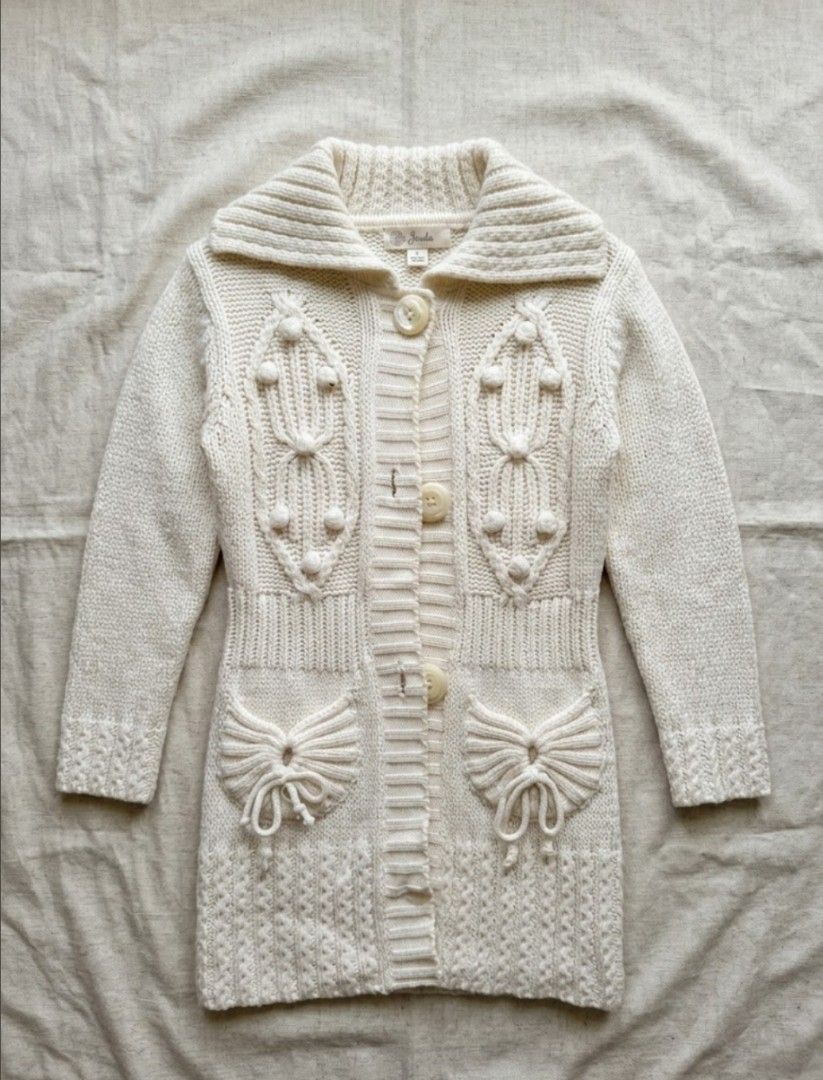 Cream Cable Knit Long Cardigan (Category: Coats, Jackets and Outerwear) located in Manila. Submitted by littlenicsfinds (Listing ID 1467079895, Image 1). Description: - Color: Cream - Style: Long cardigan with chunky shawl collar and button-front closure - Details: Intricate front knit patterns and two front pockets with bow accents - Features: Ribbed cuffs and hem line - Condition: Great for layering and keeping warm during cooler weather.