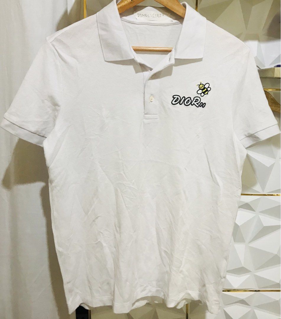 Dior Bee Embroidered White Polo Shirt (Category: Luxury Apparel) located in Rizal. Submitted by drthrifttwo (Listing ID 1466975973, Image 2). Description: - Brand: Dior - Item: Polo shirt with short sleeves and collar - Color: White - Size: Medium (21" chest x 27" length) - Material: Cotton and polyester blend - Design: Embroidered Dior logo and iconic Kaws bee patch on chest - Details: Two-button placket, made in China - Condition: Excellent / G