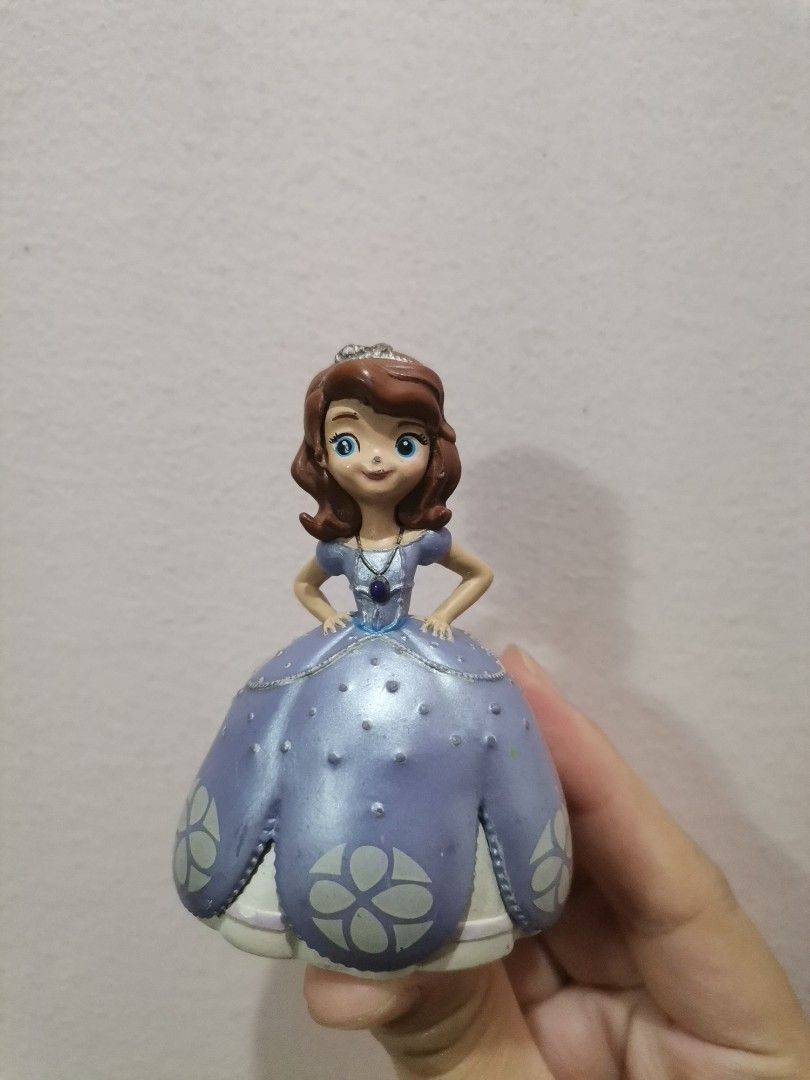 Disney Princess Sofia the First Figurine (Category: Figurines & Statues) located in Makati City. Submitted by kookybearsstuff (Listing ID 1467090679, Image 1). Description: - Character: Disney Sofia the First in her signature purple dress with white floral patterns - Size: Stands a few inches tall, perfect for display - Details: Features intricate crown, necklace pendant, and lovely facial features - Authenticity: Base stamped with Disney, made i