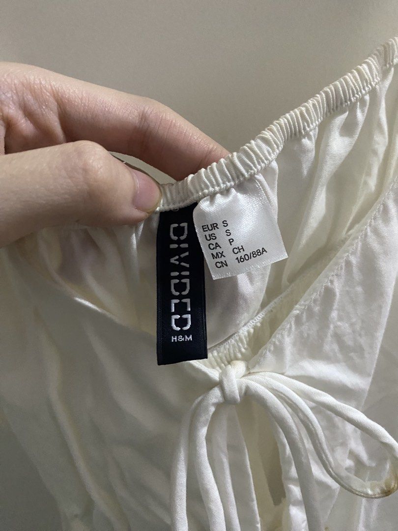 Divided H&M White Tie-Front Camisole Top (Category: Sleeveless) located in Angeles City. Submitted by kooarchives (Listing ID 1467068077, Image 3). Description: - Brand/Model: Divided by H&M - Size: S (Small) - Color: White - Details: Double tie-front closures, adjustable gathered straps, peplum hem - Material: Lightweight and breathable - Condition: Clean overall, with a small brownish stain on one ribbon tie (please check photos), can be remove