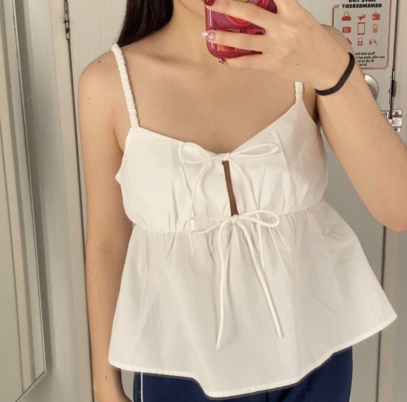 Divided H&M White Tie-Front Camisole Top (Category: Sleeveless) located in Angeles City. Submitted by kooarchives (Listing ID 1467068077, Image 1). Description: - Brand/Model: Divided by H&M - Size: S (Small) - Color: White - Details: Double tie-front closures, adjustable gathered straps, peplum hem - Material: Lightweight and breathable - Condition: Clean overall, with a small brownish stain on one ribbon tie (please check photos), can be remove