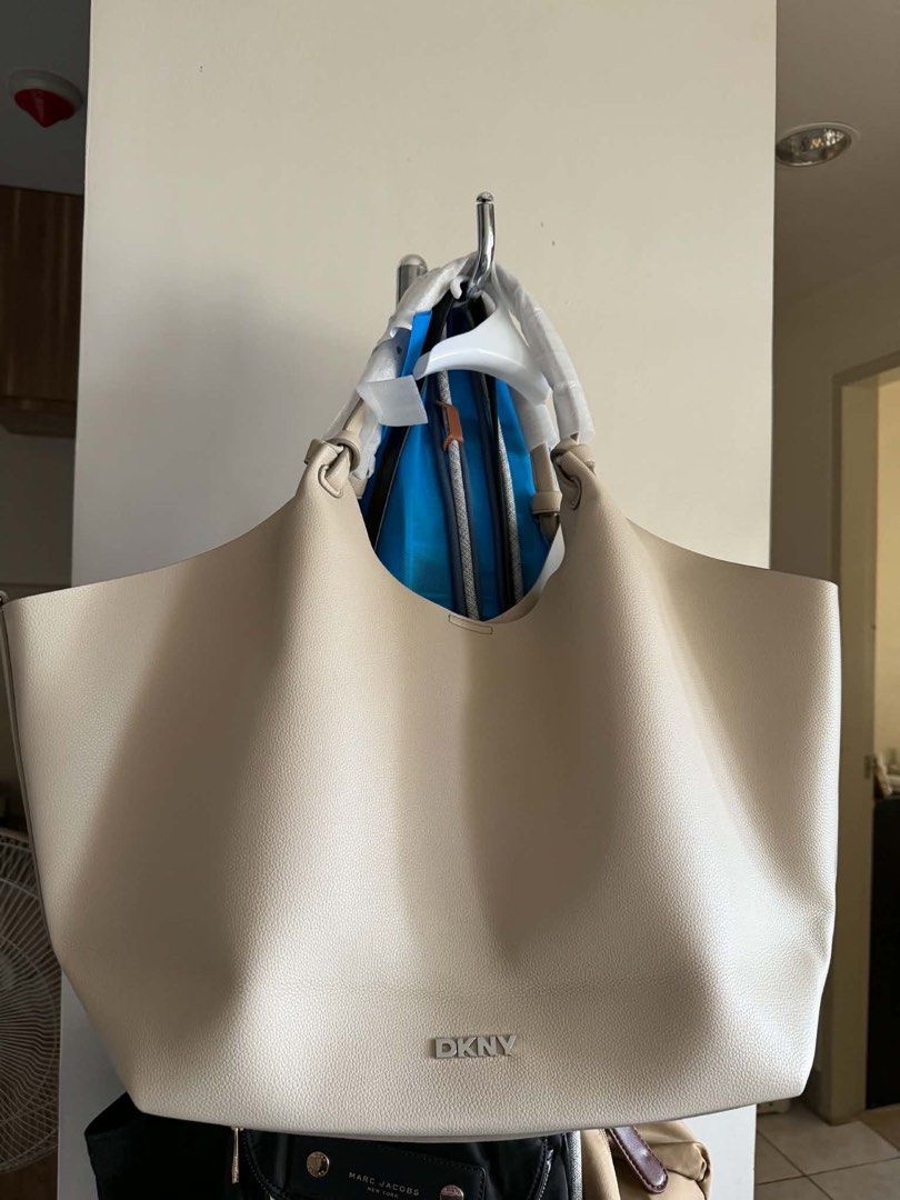 DKNY Cream Tote Bag (Category: Tote Bags) located in Santiago. Submitted by laraeavonna (Listing ID 1467164282, Image 1). Description: - Brand: DKNY - Color: Cream - Material: Textured faux leather with a slouchy shape - Hardware: Silver-tone lettering on the front - Condition: Handles still wrapped in protective plastic - Capacity: Large everyday size with plenty of interior space.