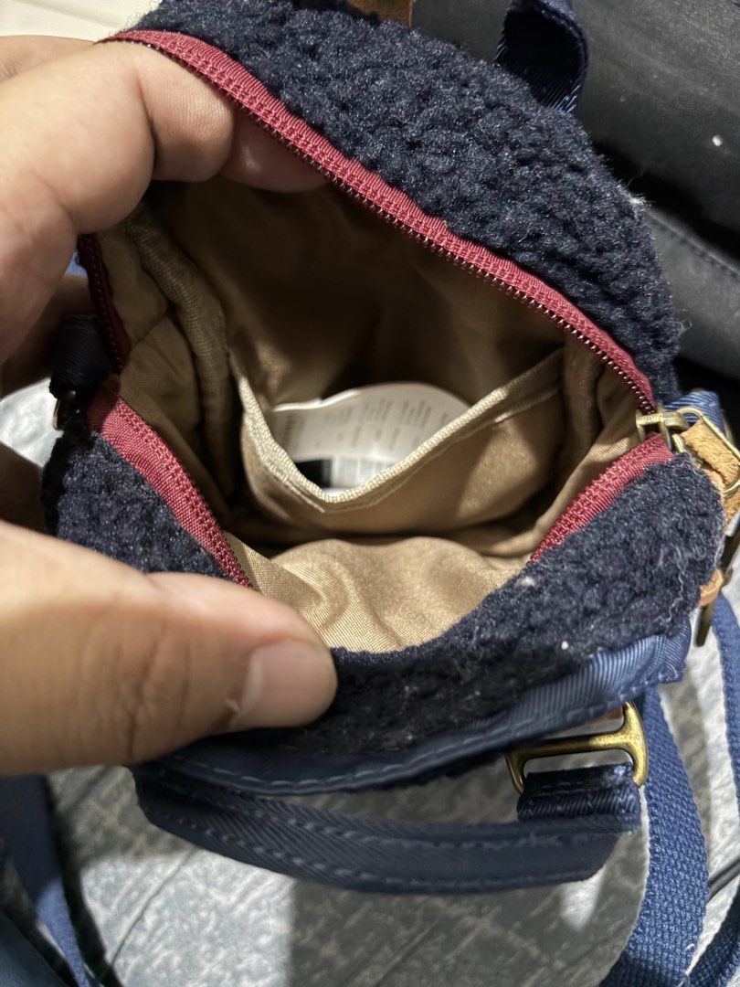 Doughnut Navy Blue Mini Crossbody Bag (Category: Cross-body Bags) located in Manila. Submitted by jjprelovedcollections2 (Listing ID 1467063285, Image 3). Description: - Brand: Doughnut - Color: Navy blue fluffy fleece with brown leather accents - Features: Front buckle pocket, inner slip pocket, and metal hardware - Condition: Brand new, hardware still wrapped in plastic with official authenticity QR hangtag attached - Strap: Detachable blue sho