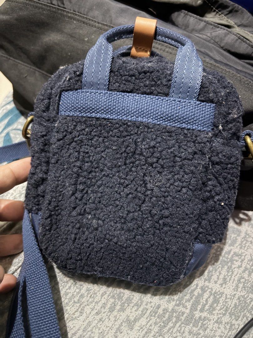 Doughnut Navy Blue Mini Crossbody Bag (Category: Cross-body Bags) located in Manila. Submitted by jjprelovedcollections2 (Listing ID 1467063285, Image 2). Description: - Brand: Doughnut - Color: Navy blue fluffy fleece with brown leather accents - Features: Front buckle pocket, inner slip pocket, and metal hardware - Condition: Brand new, hardware still wrapped in plastic with official authenticity QR hangtag attached - Strap: Detachable blue sho
