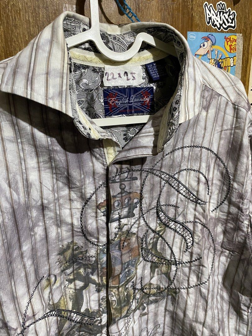 English Laundry Long Sleeve Striped Button Down Shirt (Category: Formal Shirts) located in Imus. Submitted by frootiloots4103 (Listing ID 1467153529, Image 2). Description: - Brand: English Laundry - Size: M - Material: 60% cotton, 40% polyester - Design: Grey and white stripes with unique graphic prints and chest embroidery - Details: Intricate embroidered cuffs and classic collar with paisley inner lining - Condition: Great statement piece pack
