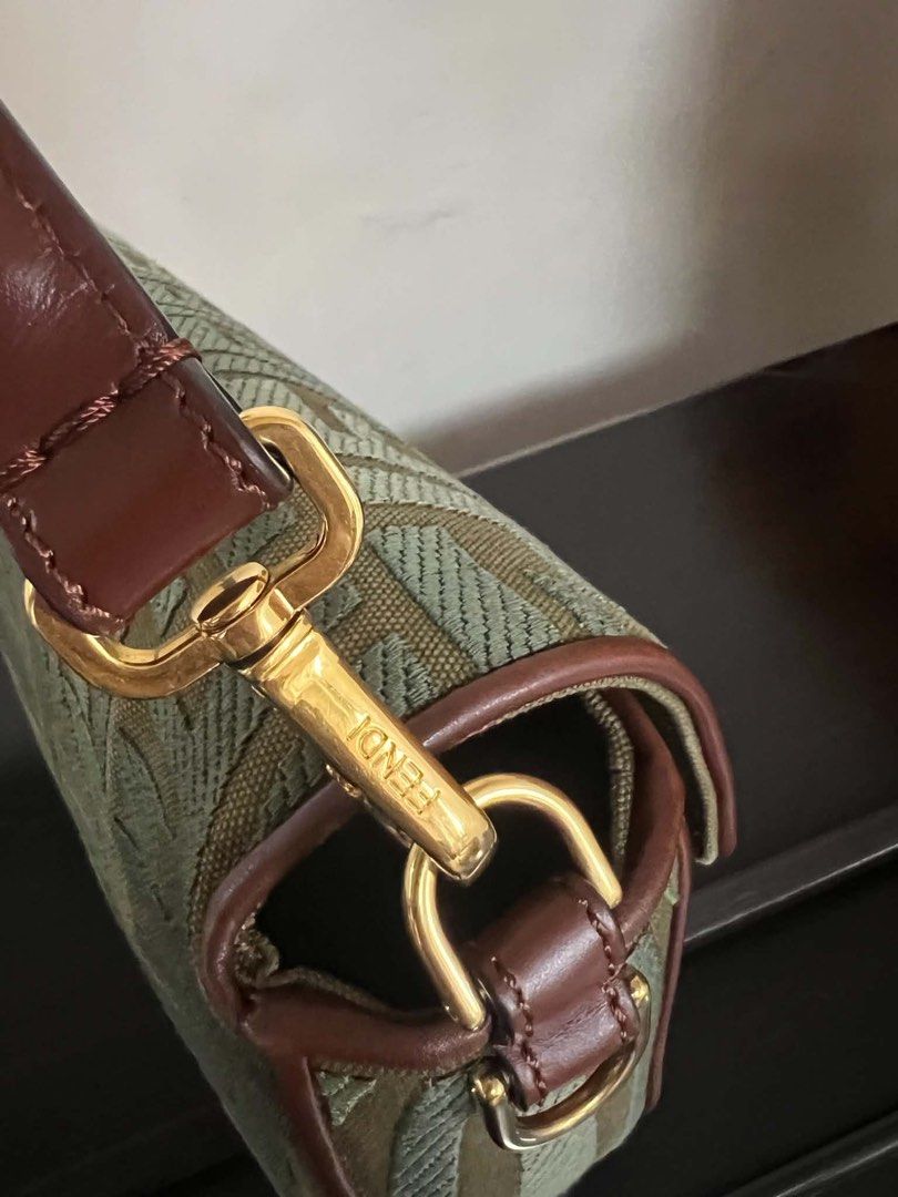 F Zucca Zucchino Canvas Shoulder Bag (Category: Luxury Bags & Wallets) located in Quezon City. Submitted by hellopatchi (Listing ID 1467003725, Image 3). Description: Fendi shoulder bag in green and brown Zucca monogram canvas. Brown leather trim and gold-tone hardware. Front flap closure featuring the signature FF logo metal buckle. Adjustable brown leather strap with engraved Fendi hardware clasps. Structured shape with compact interior. Minor 