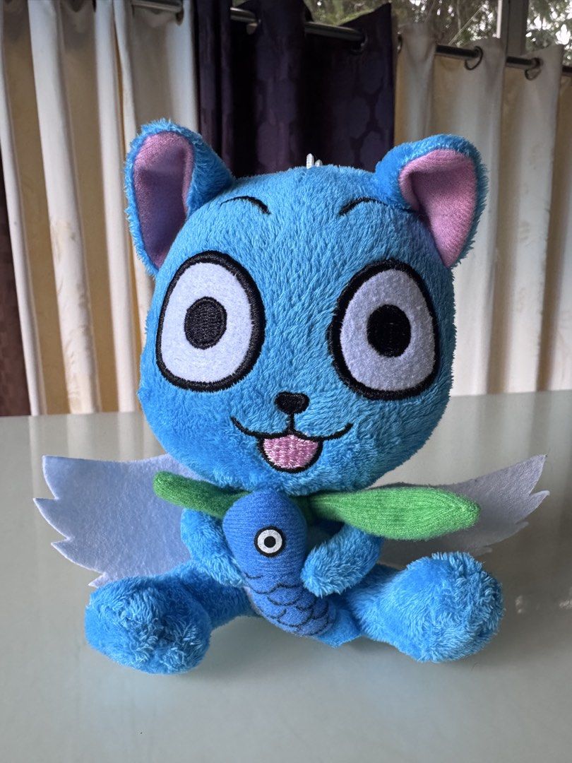 Fairy Tail Happy Plush Toy with Fish (Category: Plushies & Soft Toys) located in Caloocan City. Submitted by ciel31 (Listing ID 1467085488, Image 1). Description: - Character: Happy from Fairy Tail - Design: Bright blue fur, big white eyes, pink inner ears, and joyful expression - Accessories: Holding a blue fish with green seaweed - Features: White felt wings on the back and a white hanging loop on top.