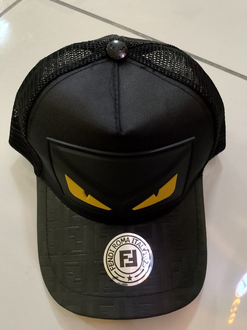 Fen di Monogram Eyes Black Trucker Cap (Category: Caps & Hats) located in Quezon City. Submitted by viaggo.travels (Listing ID 1467037462, Image 1). Description: - Brand: Fen. di - Color: Classic Black with Yellow Eye rubberized patch - Style: Trucker cap with breathable mesh back panels - Details: Embossed FF monogram pattern on the brim with original sticker - Hardware: Adjustable back strap featuring a small Fendi logo plate - Interior: Brande