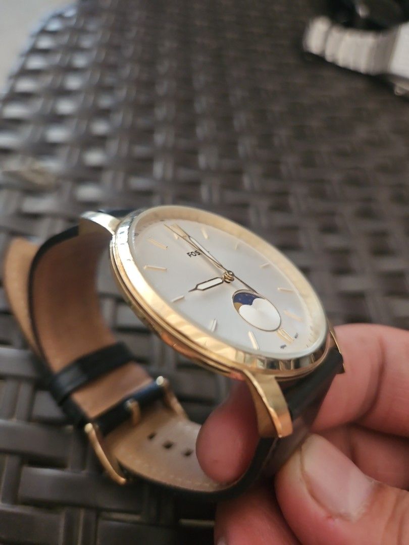 Fossil Gold Moonphase Watch with Black Leather Strap (Category: Men's Watches) located in Santa Maria. Submitted by rommelmateo (Listing ID 1466974173, Image 2). Description: - Brand: Fossil - Design: Classic gold-tone dress watch with a white dial - Features: Moonphase subdial at 3 o'clock, Roman numerals at 6 and 12, stick markers - Strap: Genuine black leather with buckle closure - Build & Durability: All stainless steel case, 5 ATM water resi