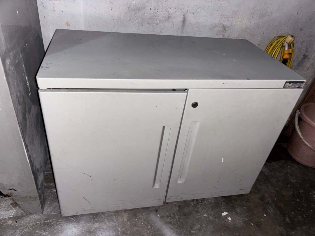 Grey Metal Office Storage Cabinet with Two Doors (Category: Office Furniture & Fixtures) located in Manila. Submitted by cleverocean.10acf9 (Listing ID 1467060057, Image 1). Description: - Grey metal storage cabinet with sturdy construction - Features two doors with vertical handles and a working key lock on the right door - Flat top surface provides extra space for placement - Ideal for office, garage, or workshop organization - Condition: Shows