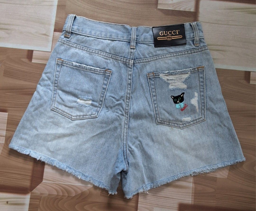 Gucci Denim Short (Category: Shorts) located in Makati City. Submitted by justget8 (Listing ID 1467126707, Image 1). Description: - Size: W-25-27 L-14 - Details: Distressed accents on front and back pockets - Accents: Adorable black embroidered cat patch with blue bow on the right back pocket - Branding: Authentic leather Gucci logo patch on the back waistband - Closure: Metal button and front zipper.