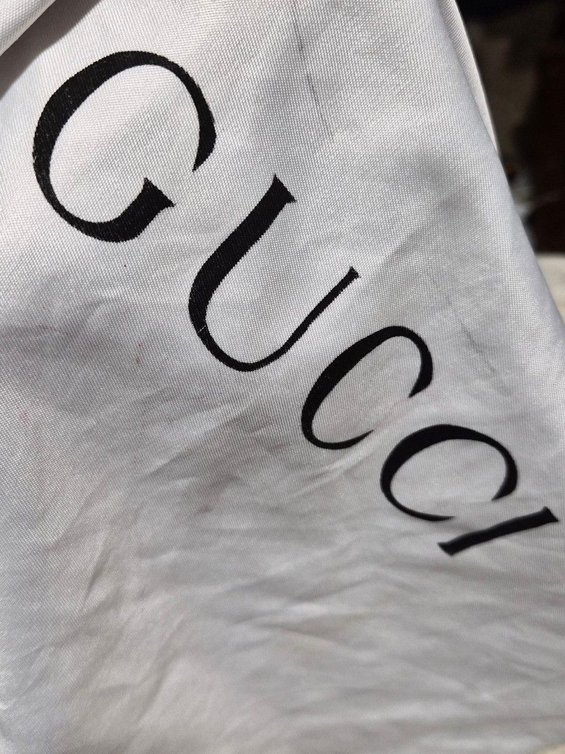 Gucci Dust Bag White Drawstring 14 x 15 inches (Category: Luxury Bags & Wallets) located in Mandaue City. Submitted by chuchi152615 (Listing ID 1466972368, Image 2). Description: - white Gucci dust bag featuring the classic black logo lettering - Convenient drawstring closure at the top - Dimensions: Approximately 14 inches x 14.5 inches - Condition: Has some minor smudges and small marks on the fabric surface - Ideal for storing designer bags an