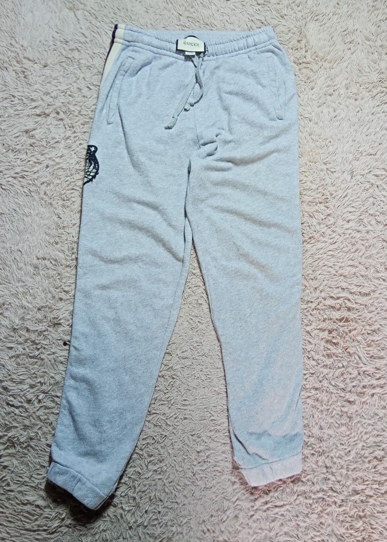 Gucci Tiger Stripe Grey Joggers Sweatpants (Category: Joggers) located in Lucban. Submitted by aeronroyyy (Listing ID 1466988916, Image 2). Description: - Authentic grey Gucci sweatpants made in Italy - Crafted from soft and comfortable cotton fleece - Adjustable drawstring waist and convenient side pockets - Signature striped tape with repeated block Gucci lettering down both legs - Distinctive embroidered tiger head patch near the right hem - R