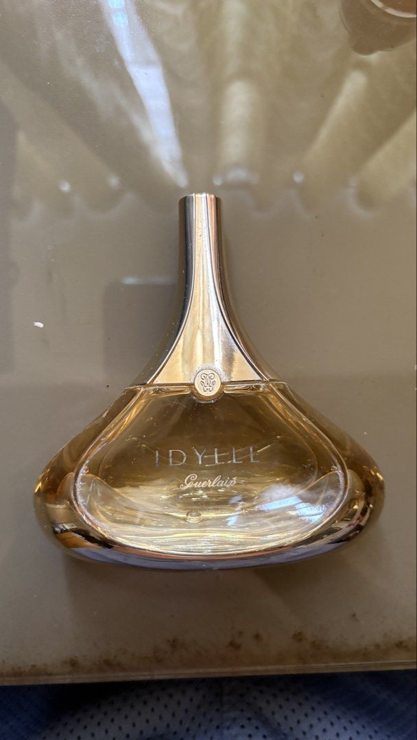 Guerlain Idylle Eau de Parfum (Category: Fragrance & Deodorants) located in Bacoor. Submitted by shoesforsale.com (Listing ID 1467141431, Image 1). Description: - Authentic Guerlain Idylle perfume - Iconic gold drop-shaped design with engraved logo - Clear glass base revealing the amber fragrance - Features silver 'Idylle' and 'Guerlain' lettering - Approximately half full, perfect for trying the scent - Beautiful and classic vanity display piece