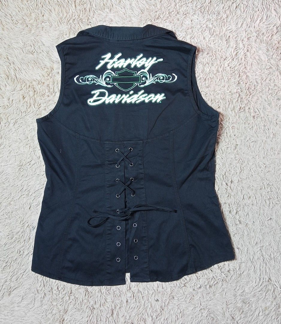 Harley Davidson Black Embroidered Zip Vest Size L (Category: Vests) located in Lucban. Submitted by aeronroyyy (Listing ID 1466988362, Image 2). Description: Black Harley-Davidson sleeveless zip-up vest in size Large. White and green embroidery lettering and graphics across the back and front chest. Metal branded zipper pull. Corset-style lace-up back detail with grommets. Collared neckline with two front chest pockets. 98 percent cotton and 2 pe