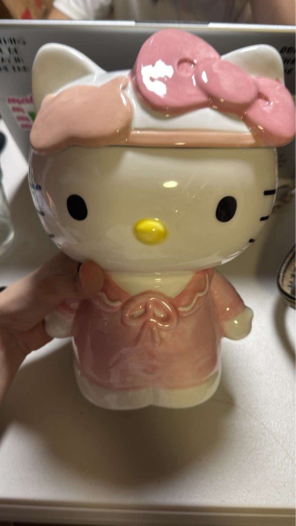 Hello Kitty ceramic cookie jar container with lid (Category: Food Organization & Storage) located in Manila. Submitted by janetecson05 (Listing ID 1467065110, Image 1). Description: - Authentic Kitty ceramic container with a cute big pink bow on top - Wears a matching pink outfit with a stylish collar and bow design - Features a glossy finish all over with a convenient removable lid - Great size for storing snacks or small trinkets on your desk o