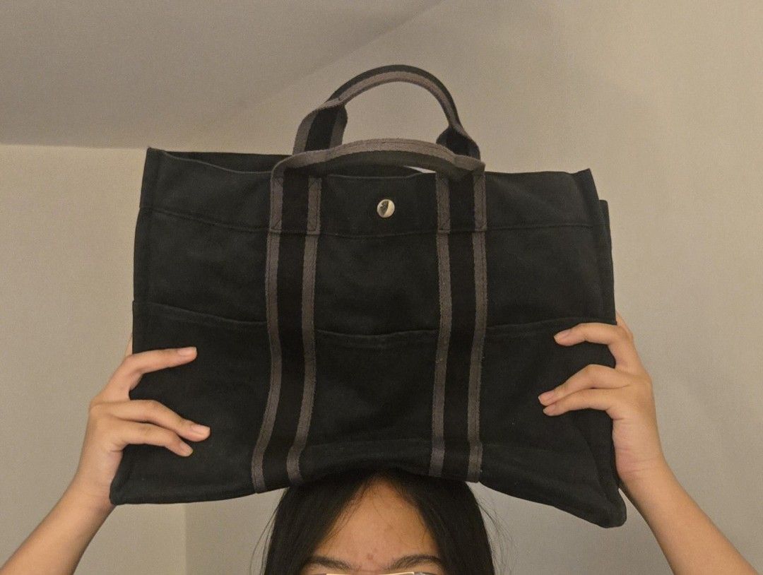 Authentic Hermes Fourre Tout Tote Bag Black Canvas (Category: Tote Bags) located in Quezon City. Submitted by PreLovedByMrsAL (Listing ID 1467038989, Image 1). Description: - Brand: Hermès Fourre Tout Tote - Material: Durable solid black canvas with dark grey straps and top handles - Closure: Silver-tone snap button at the top center - Pockets: Multiple exterior slip pockets on front and back for easy storage - Design: Structured rectangular shap