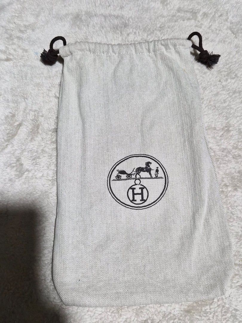 Hermès herringbone dust bag with drawstring closure 12 x 7 inches (Category: Baby Monitors) located in Mandaue City. Submitted by chuchi152615 (Listing ID 1466972985, Image 1). Description: - Hermès dust bag - Made from premium beige herringbone fabric - Features dark brown drawstrings on both sides with knotted ends - Clear central circular logo with the classic horse-drawn carriage and 'H' - Clean fabric and pristine print - Ideal for storing l
