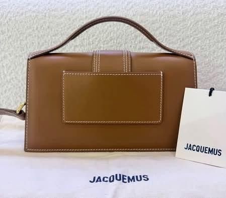 Jacquemus Brown Leather Shoulder Bag (Category: Luxury Bags & Wallets) located in Manila. Submitted by catpanganiban_ (Listing ID 1467118610, Image 3). Description: - Authentic Jacquemus brown leather top handle bag - Chic white contrast stitching and gold-tone metal hardware - Signature front lettering logo and back slip pocket - Structured flap design with secure closure - Includes detachable shoulder strap for versatile wear - Comes with origi