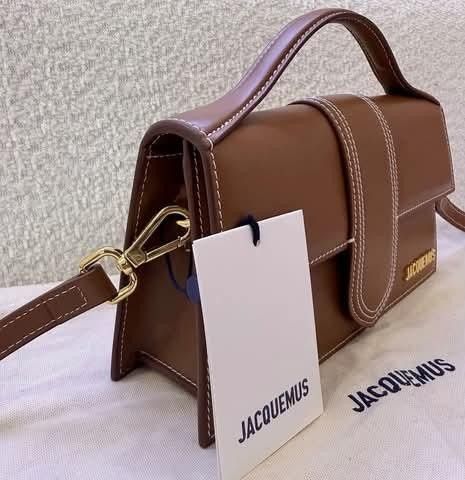 Jacquemus Brown Leather Shoulder Bag (Category: Luxury Bags & Wallets) located in Manila. Submitted by catpanganiban_ (Listing ID 1467118610, Image 2). Description: - Authentic Jacquemus brown leather top handle bag - Chic white contrast stitching and gold-tone metal hardware - Signature front lettering logo and back slip pocket - Structured flap design with secure closure - Includes detachable shoulder strap for versatile wear - Comes with origi