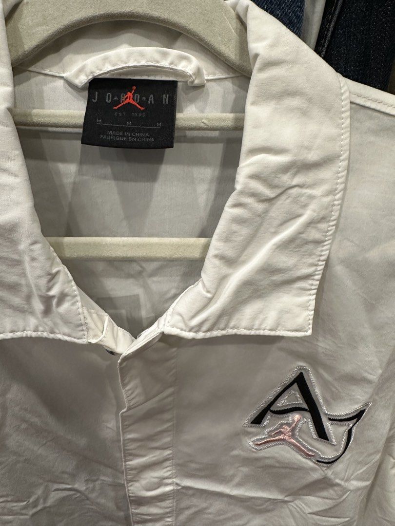 Jordan White Short Sleeve Button Up Shirt (Category: Formal Shirts) located in Makati City. Submitted by hehehekdeg (Listing ID 1467032267, Image 3). Description: - Brand: Jordan - Style: Short sleeve button-up shirt with camp collar - Size: Medium - Material: Cotton and nylon blend - Design details: Black hem, stitched AJ logo with pink Jumpman on the chest, and large black JORDAN lettering across the back - Condition: Clean, excellent for casua