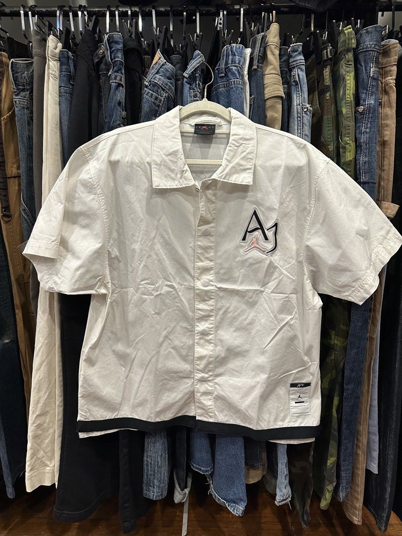Jordan White Short Sleeve Button Up Shirt (Category: Formal Shirts) located in Makati City. Submitted by hehehekdeg (Listing ID 1467032267, Image 1). Description: - Brand: Jordan - Style: Short sleeve button-up shirt with camp collar - Size: Medium - Material: Cotton and nylon blend - Design details: Black hem, stitched AJ logo with pink Jumpman on the chest, and large black JORDAN lettering across the back - Condition: Clean, excellent for casua