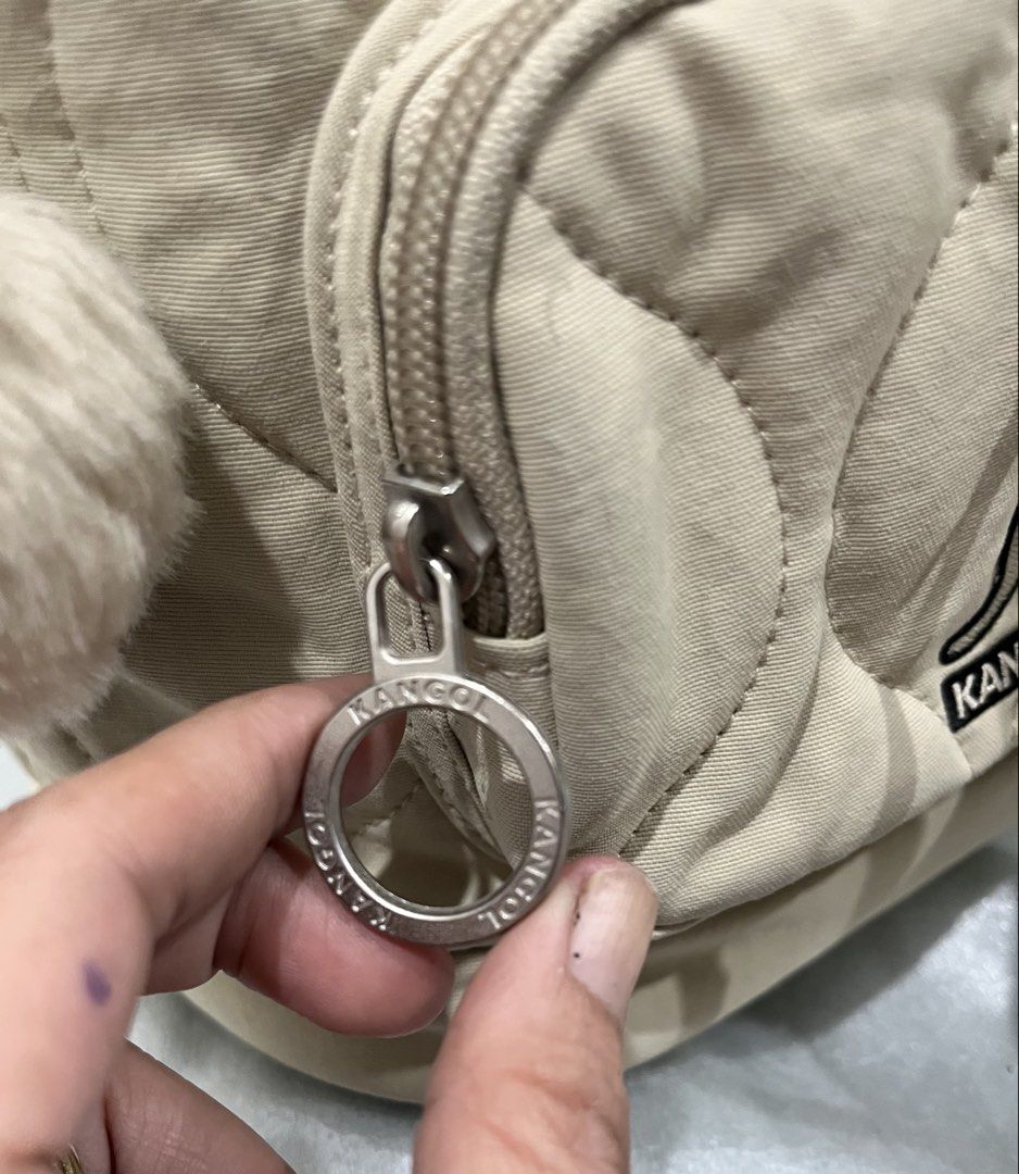 Kangol Quilted Beige Bucket Bag with Pompom (Category: Shoulder Bags) located in Talisay. Submitted by cherylu (Listing ID 1466976209, Image 3). Description: - Brand: Kangol - Color: Beige - Style: Quilted bucket bag with drawstring closure and top grab handle - Hardware: Silver-tone with engraved hooks and circular logo zipper pull - Pockets: Front zippered pocket - Extras: Includes detachable furry pompom charm and Kangol kangaroo leather keych