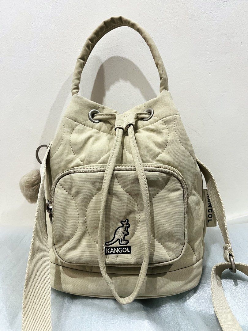 Kangol Quilted Beige Bucket Bag with Pompom (Category: Shoulder Bags) located in Talisay. Submitted by cherylu (Listing ID 1466976209, Image 1). Description: - Brand: Kangol - Color: Beige - Style: Quilted bucket bag with drawstring closure and top grab handle - Hardware: Silver-tone with engraved hooks and circular logo zipper pull - Pockets: Front zippered pocket - Extras: Includes detachable furry pompom charm and Kangol kangaroo leather keych