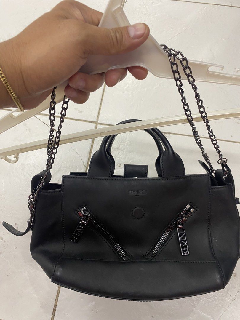 Kenzo Black Leather Tote Bag with Chain Strap (Category: Tote Bags) located in Alburquerque. Submitted by zanegavynn43872 (Listing ID 1466976550, Image 1). Description: - Brand: Kenzo - Color: Classic black - Material: Premium leather - Features: Twin top handles, chain shoulder strap, dual front zippered pockets with branded pulls, and secure snap button closure - Interior: Includes a slip pocket stamped with the Kenzo logo - Size: Compact daily