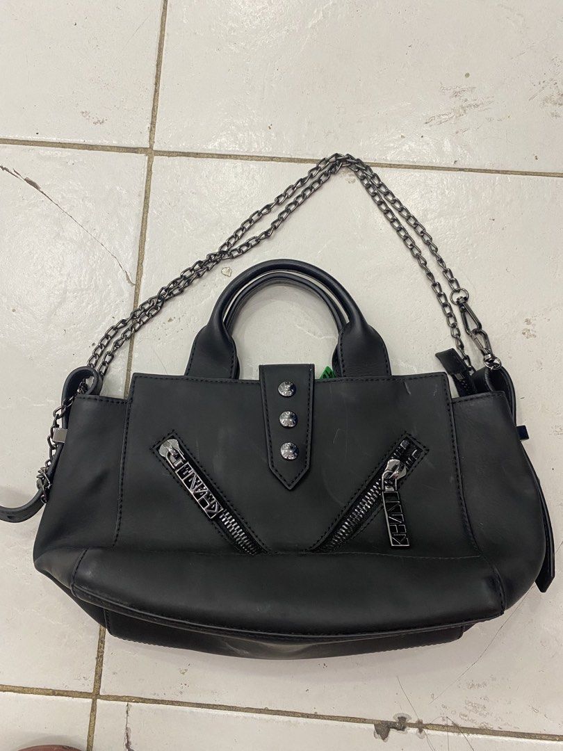 Kenzo Black Leather Tote Bag with Chain Strap (Category: Tote Bags) located in Alburquerque. Submitted by zanegavynn43872 (Listing ID 1466976550, Image 2). Description: - Brand: Kenzo - Color: Classic black - Material: Premium leather - Features: Twin top handles, chain shoulder strap, dual front zippered pockets with branded pulls, and secure snap button closure - Interior: Includes a slip pocket stamped with the Kenzo logo - Size: Compact daily