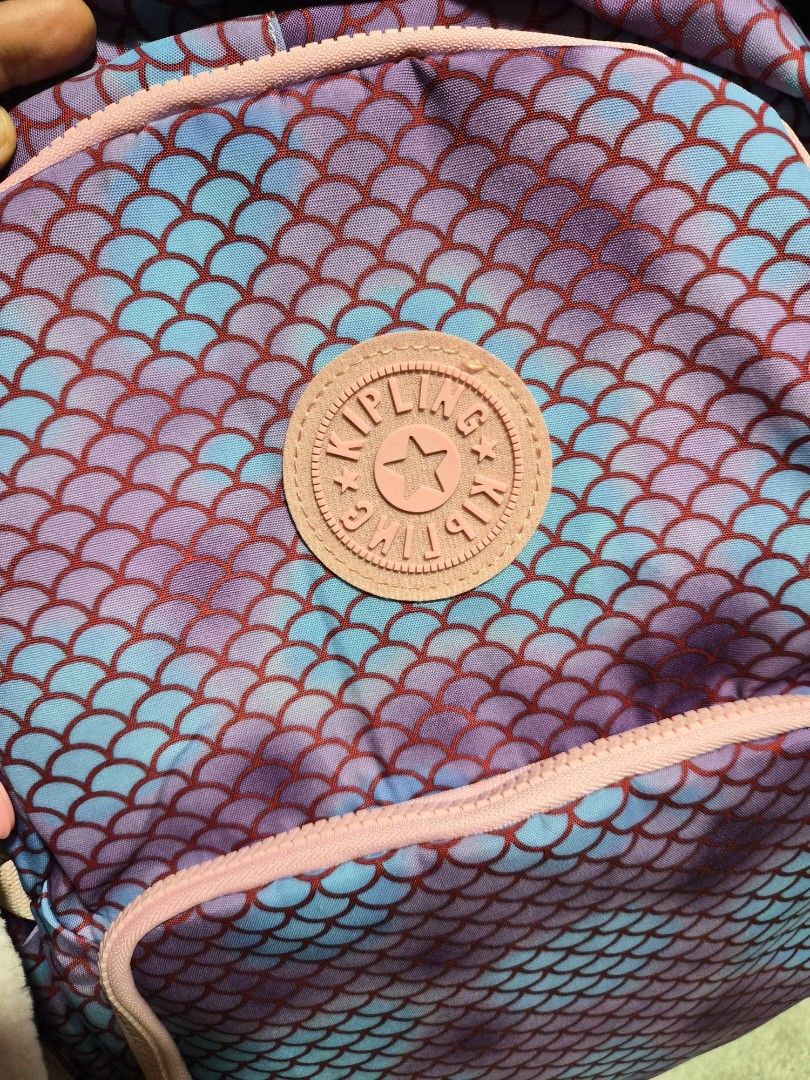 Kipling Mermaid Scale Pink Blue School Backpack Bag (Category: Backpacks) located in Mandaue City. Submitted by chuchi152615 (Listing ID 1466985514, Image 2). Description: Kipling backpack with purple and blue mermaid scale print. Pink zippers and straps throughout. Includes the matching light pink monkey keychain dangling from the front zipper. Padded shoulder straps with chest buckle for secure carrying. Multiple front zip compartments for stor