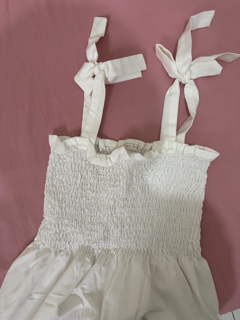 La Coco Babe White Smocked Sundress with Tie Straps (Category: Dresses) located in Caloocan City. Submitted by nikkiepie704949 (Listing ID 1466975264, Image 1). Description: - Brand: La Coco Babe - Color: White - Style: Sleeveless sundress with flared skirt hitting above the knee - Details: Stretchy smocked bodice and cute adjustable tie straps - Fabric: Super breezy and lightweight, perfect for warm weather.