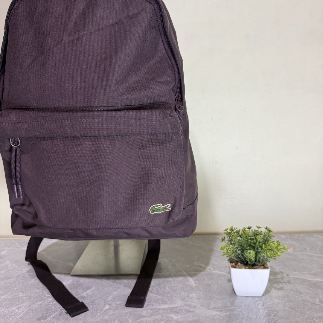 Lacoste Dark Purple Canvas Backpack (Category: Backpacks) located in Bago City. Submitted by g___shop (Listing ID 1467102552, Image 2). Description: - Authentic Lacoste dark purple canvas backpack - Main zip compartment with front zip pocket and branded cord pullers - Padded shoulder straps and mesh back panels for all-day comfort - Classic embroidered green crocodile logo near the bottom corner - Clean, stylish shape perfect for everyday casual 