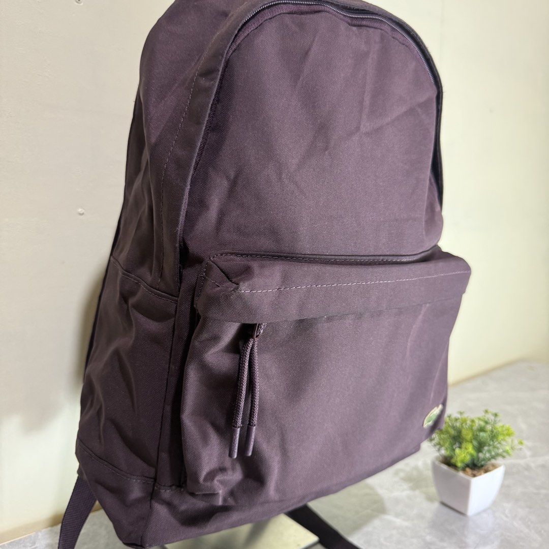 Lacoste Dark Purple Canvas Backpack (Category: Backpacks) located in Bago City. Submitted by g___shop (Listing ID 1467102552, Image 3). Description: - Authentic Lacoste dark purple canvas backpack - Main zip compartment with front zip pocket and branded cord pullers - Padded shoulder straps and mesh back panels for all-day comfort - Classic embroidered green crocodile logo near the bottom corner - Clean, stylish shape perfect for everyday casual 