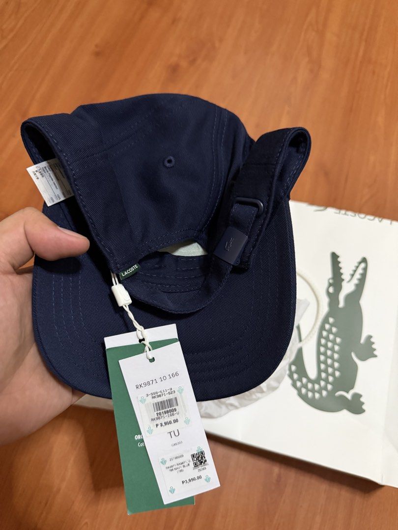 Lacoste RK9871 Navy Blue Baseball Cap (Category: Caps & Hats) located in Batangas. Submitted by bullet909 (Listing ID 1467135027, Image 3). Description: Navy blue Lacoste baseball cap with green crocodile logo embroidery on the front. Adjustable strap closure at the back with branded hardware. Original tags attached, paper bag and tissue wrapping included. Classic six-panel design, standard fit. Clean dark blue color matches practically anything.
