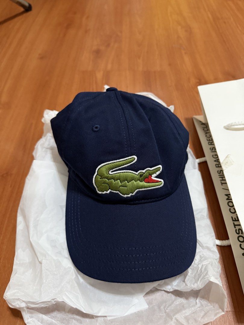 Lacoste RK9871 Navy Blue Baseball Cap (Category: Caps & Hats) located in Batangas. Submitted by bullet909 (Listing ID 1467135027, Image 2). Description: Navy blue Lacoste baseball cap with green crocodile logo embroidery on the front. Adjustable strap closure at the back with branded hardware. Original tags attached, paper bag and tissue wrapping included. Classic six-panel design, standard fit. Clean dark blue color matches practically anything.