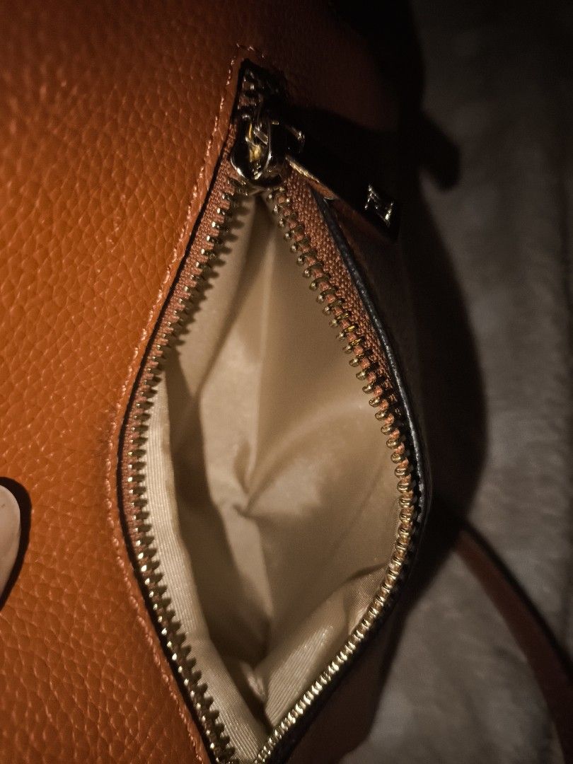 Leather Sling bag (Category: Shoulder Bags) located in Manila. Submitted by ad002021 (Listing ID 1467025872, Image 2). Description: Vibrant brown orange textured faux leather handbag with chic gold hardware. Features a silky beige interior with pockets, a structured base with protective metal feet, and includes a strap. Stylish and functional for everyday use!.