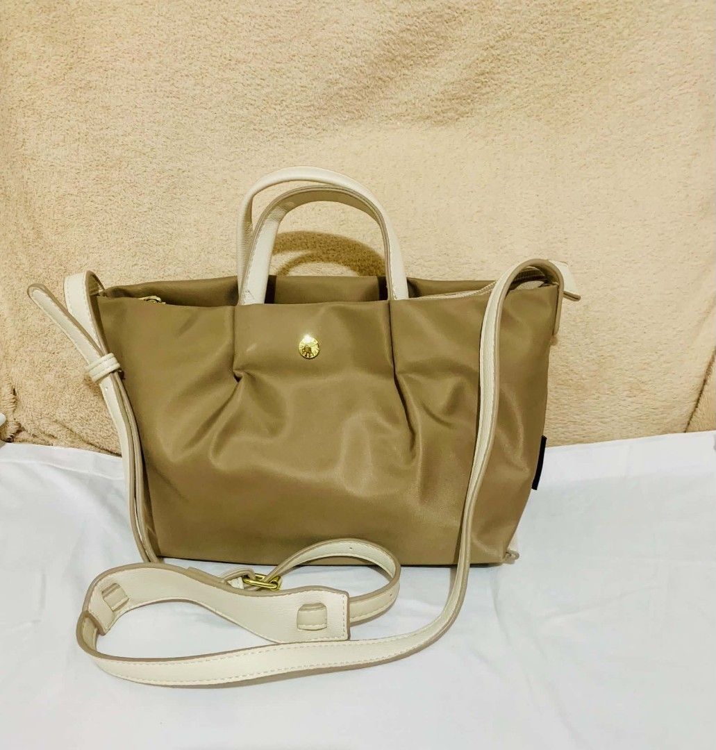 Legato Largo Bag (Category: Cross-body Bags) located in Dasmarinas. Submitted by pepperronnie (Listing ID 1464628803, Image 3). Description: This is a neutral beige multi-way tote & crossbody bag 🤎 ✨ Details: - Color: Warm taupe/beige body with cream/white handles & adjustable strap ​ - Material: Lightweight, smooth nylon + faux leather accents + gold snap button detail ​ - Versatile: Carry as a handbag/tote OR use the detachable strap for shoul