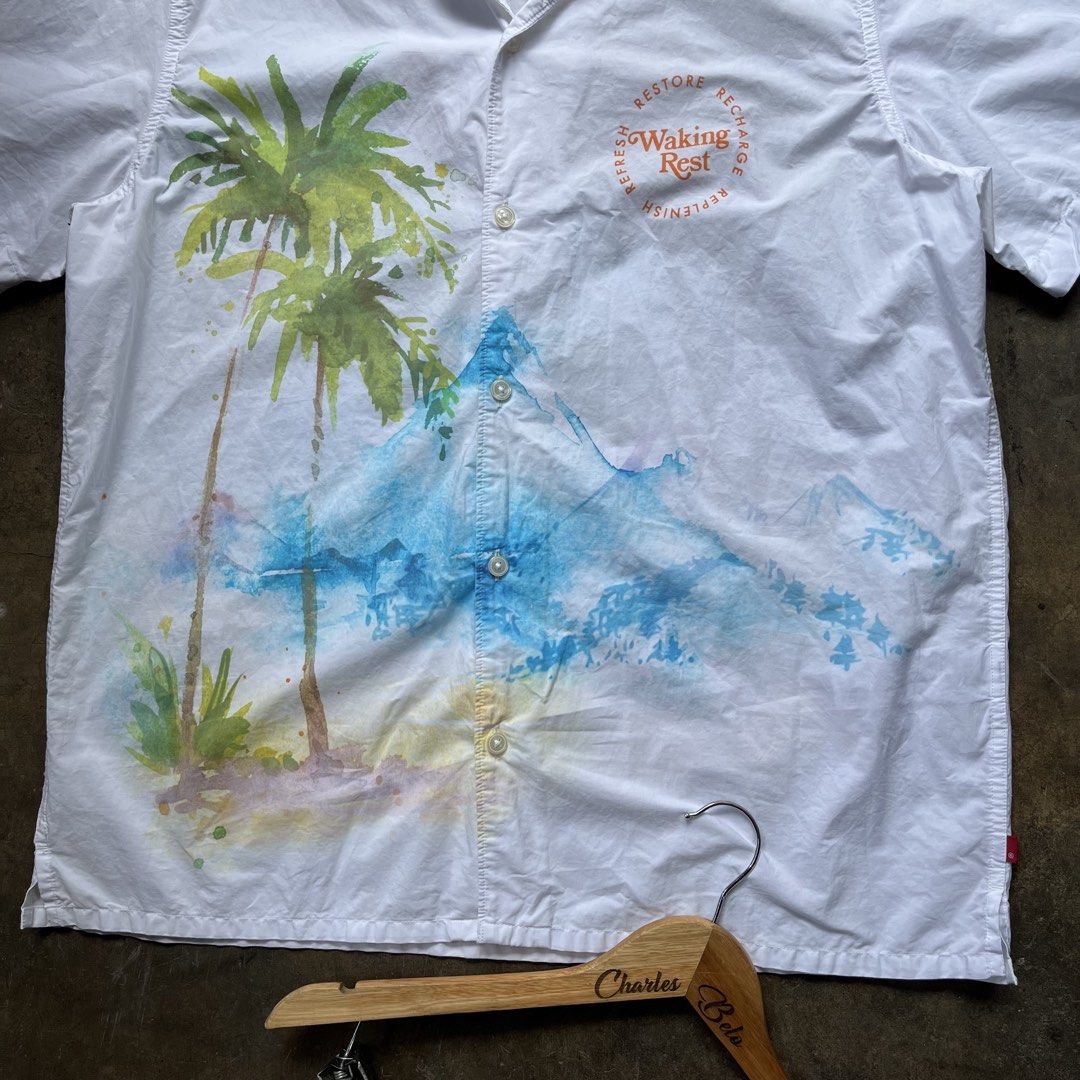 Levi's Relaxed Fit Shirt (Category: Tshirts & Polo Shirts ) located in Davao. Submitted by charlesole52665 (Listing ID 1467140236, Image 3). Description: - Brand: Levi's - Style: Relaxed fit short-sleeve button-up shirt - Size: Large - Color: White with watercolor palm tree & mountain print - Details: Small "Waking Rest" chest graphic, standard collar, front button closure - Condition: Excellent / Pre-loved (ready to wear).