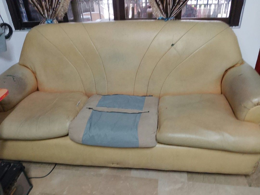Living room sofa set and armchairs (Category: Sofas) located in Quezon City. Submitted by jimi_1999 (Listing ID 1467030945, Image 2). Description: ‼️PRICE NEGOTIABLE‼️ - Needs upholstery. - Foam insides intact. RFS: Buying a new set of couches. - Complete living room set: 1 large sofa and 2 armchairs - Solid frame construction ready for a makeover - Original yellow-beige leather shows visible wear, stains, and scratches - Includes one blue/beige 