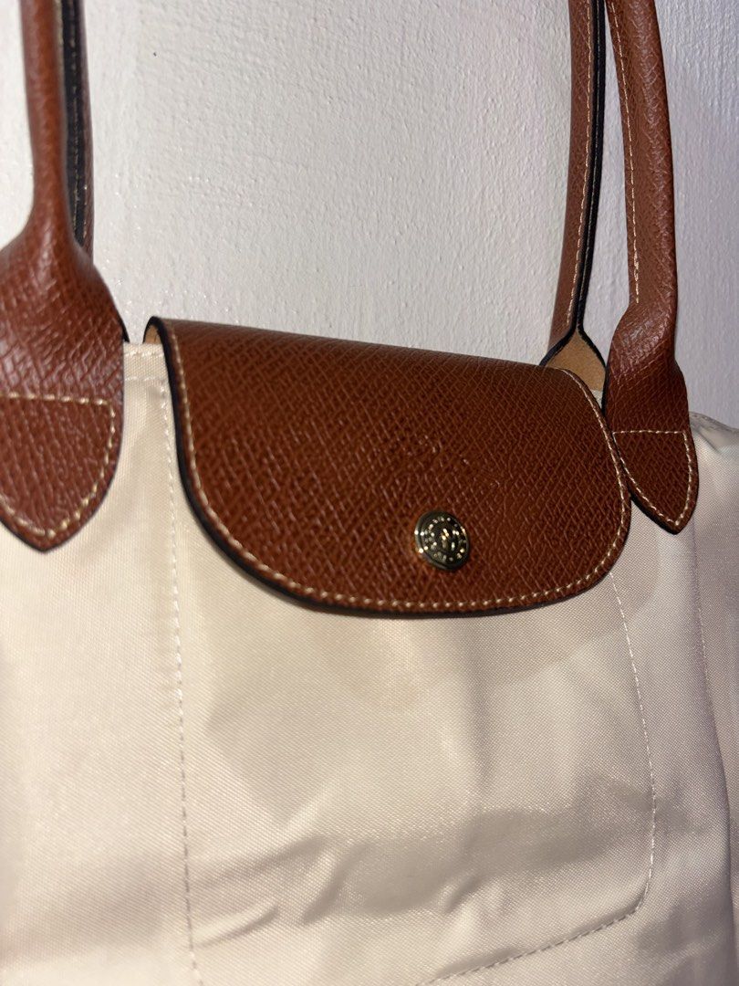 Longchamp Le Pliage Beige Tote Bag (Category: Luxury Bags & Wallets) located in Tarlac. Submitted by chosowakatoshi (Listing ID 1467095810, Image 2). Description: -Longchamp tote bag - Elegant beige nylon body with structured brown leather trim - Secure front flap with snap button closure - Classic gold-tone hardware details - Clean leather handles with nice contrast stitching - Spacious and perfect for daily use or travel - RUSH SALE / PM for in