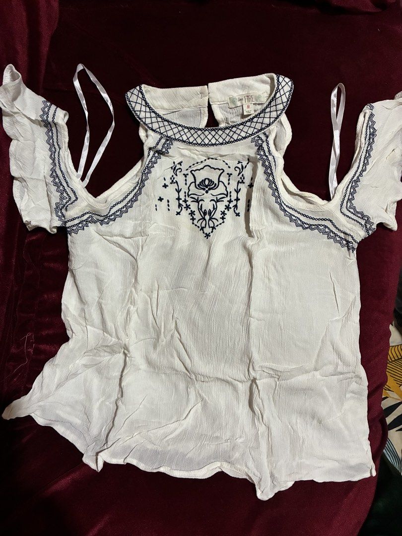 Love Fire White Cold Shoulder Embroidered Blouse Size M (Category: Blouses) located in Quezon City. Submitted by judsnasps (Listing ID 1467122290, Image 1). Description: - Brand: Love Fire - Size: Medium - Color: White with dark blue embroidery details - Design: Cold shoulder with ruffle sleeves and back neck button closure - Material: Lightweight fabric, ideal for warm weather - Condition: Clean and ready to wear.