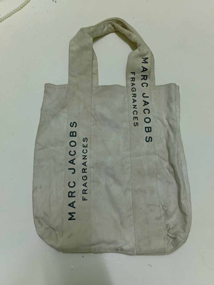 Marc Jacobs Fragrances Canvas Tote Bag (Category: Tote Bags) located in Manila. Submitted by daphnefinds1 (Listing ID 1467102693, Image 2). Description: - Brand: Marc Jacobs Fragrances - Color: Off-white with bold black block lettering on both sides - Material: Sturdy canvas with durable fabric handles - Design: Open-top utility bag for easy daily carry - Authenticity: Features interior tag with care instructions and manufacture details - Conditi