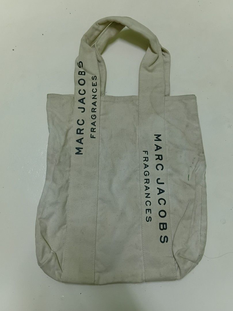 Marc Jacobs Fragrances Canvas Tote Bag (Category: Tote Bags) located in Manila. Submitted by daphnefinds1 (Listing ID 1467102693, Image 1). Description: - Brand: Marc Jacobs Fragrances - Color: Off-white with bold black block lettering on both sides - Material: Sturdy canvas with durable fabric handles - Design: Open-top utility bag for easy daily carry - Authenticity: Features interior tag with care instructions and manufacture details - Conditi