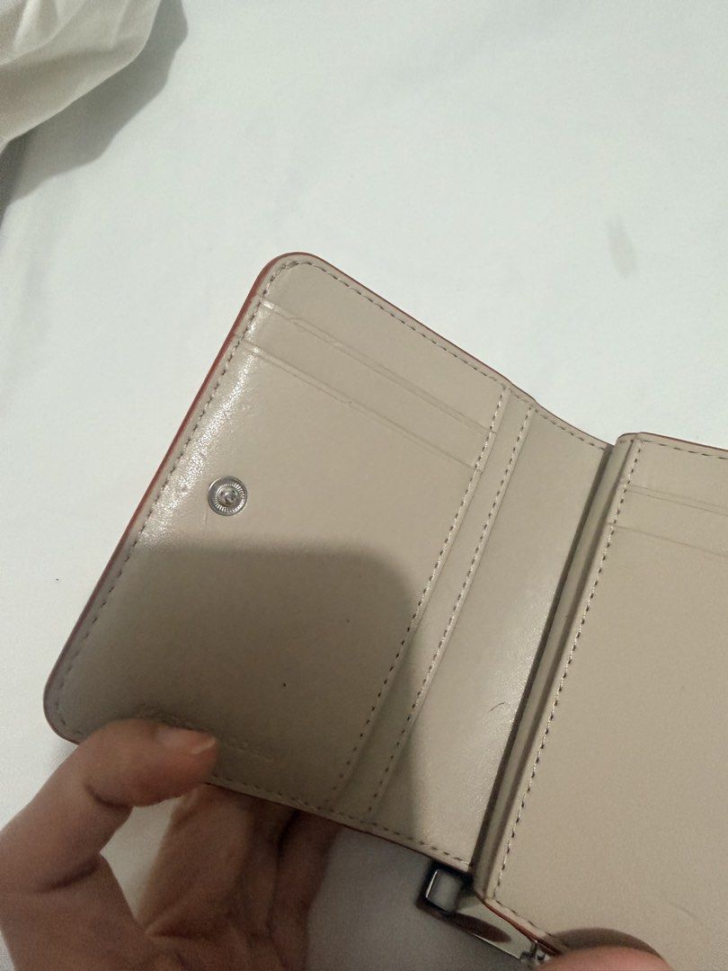 Marc Jacobs Orange Saffiano Leather Compact Bifold Wallet (Category: Wallets & Card holders) located in Cebu City. Submitted by cutexoxoshop (Listing ID 1466973588, Image 3). Description: - Brand: Marc Jacobs - Material: Durable Saffiano leather in bright orange - Hardware: Silver-tone with embossed front lettering - Closure: Secure snap closure - Interior: Beige lining with multiple card slots and a separate zippered coin compartment - Size: Com