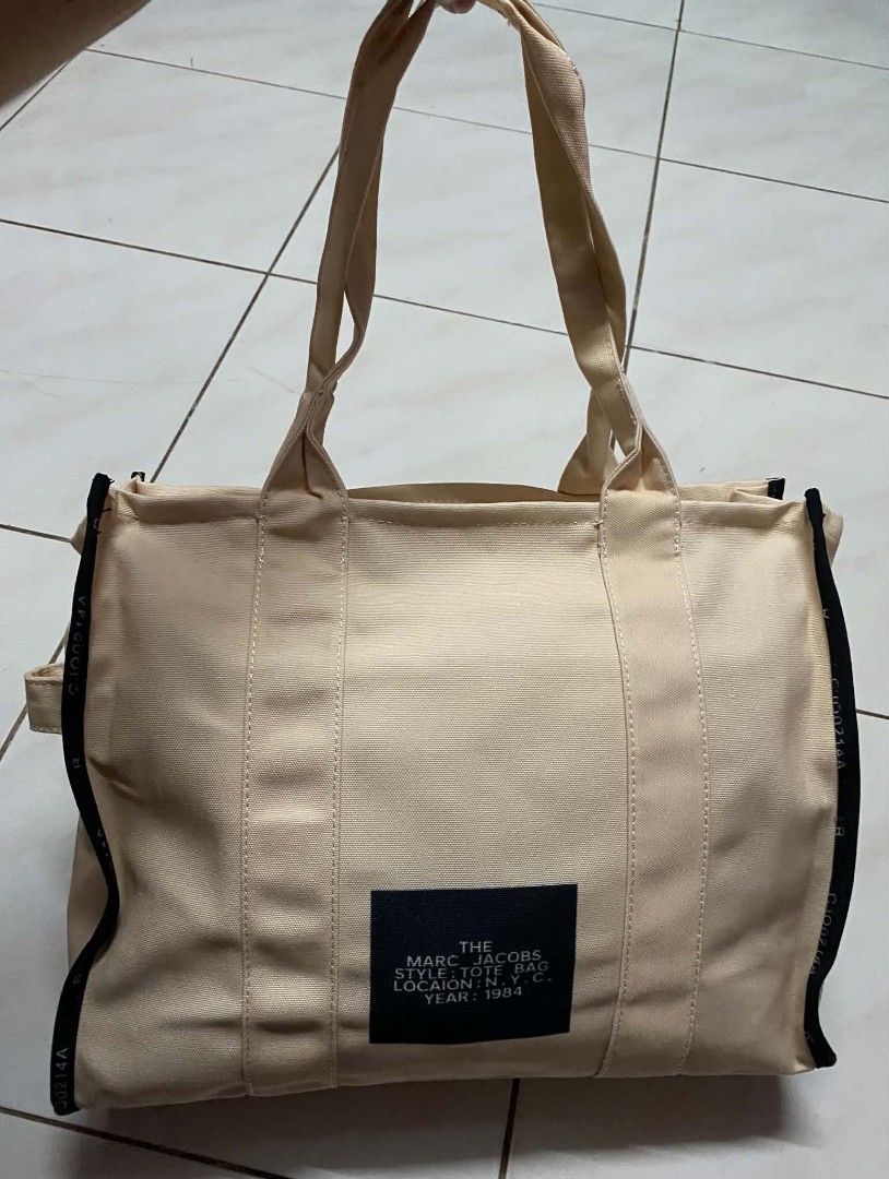 Marc Jacobs The Tote Bag Canvas (Category: Tote Bags) located in Manila. Submitted by gutierrez23265 (Listing ID 1467139743, Image 2). Description: - Marc Jacobs canvas tote bag in classic beige - Features bold statement lettering across the front - Secure top zipper closure to keep your belongings safe - Black fabric interior lining complete with a handy slip pocket - Sturdy dual carry handles for comfortable everyday use - Style number: M001704