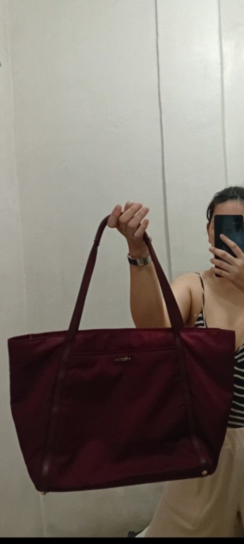 MAROON TUMI LARGE SHOULDER TOTE (Category: Luxury Bags & Wallets) located in Manila. Submitted by eriiicaspage (Listing ID 1467043512, Image 2). Description: PreOwned Lightly Used TUMI LARGE VOYAGEUR MAROON NYLON Q TOTE SHOULDER BAG - Color: Burgundy nylon with brown leather straps and gold-tone hardware - Closure: Secure zip-top closure - Exterior: Front slip pocket with signature metal TUMI logo plaque - Interior: Spacious compartment for daily