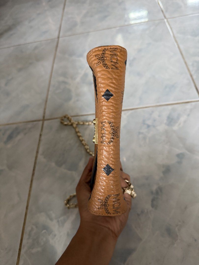 MCM Cognac Visetos Monogram Chain Crossbody Bag (Category: Luxury Bags & Wallets) located in Manila. Submitted by kayecake_ (Listing ID 1467167789, Image 3). Description: - Brand: MCM - Color/Pattern: Cognac with classic monogram print and black diamond accents - Hardware: Gold-tone - Strap: Chain strap - Closure: Front latch lock - Interior: Fabric-lined with 1 zippered pocket - Exterior: Back slip pocket for quick access - Size: Compact, ideal 