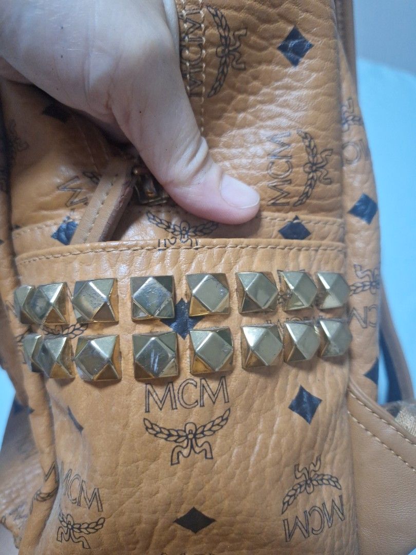 MCM Stark Studded Visetos Coated Canvas Backpack Cognac (Category: Luxury Bags & Wallets) located in Manila. Submitted by loydamariano (Listing ID 1466970934, Image 3). Description: - Brand/Model: Classic MCM Stark Backpack - Material/Color: Iconic Visetos monogram leather in Cognac - Details: Vertical pyramid studs, front zip pocket, spacious main compartment, and gold-tone hardware - Design: Flat sturdy base keeps the bag upright when placed do